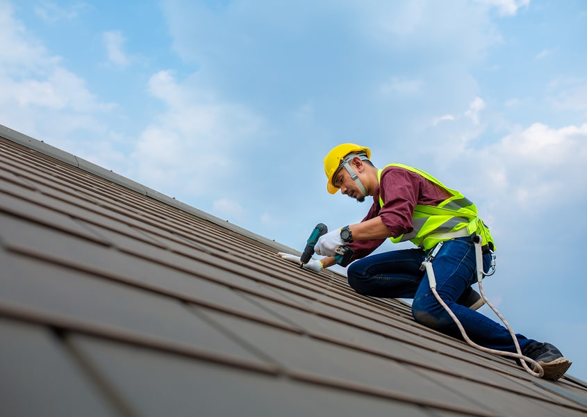 Man in a hard hat conducting roof replacement service.